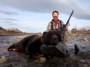 Hunter with a Grizzly Bear in a Stream